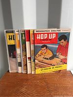 Front view of seven vintage Hop Up & Motor Life magazines stacked upright, showing colorful 1950s-era illustrated covers.