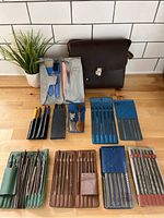 Top-down view of the collection showing multiple sets of needle files, a glass cutter, and small precision tools, all arranged neatly on a wooden surface.