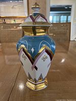 Front view of the hand painted porcelain vase showing colorful geometric and floral design with gold accents.