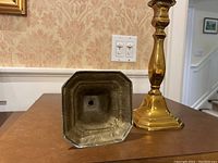 Bottom view of one brass candlestick showing it is hollow with a central hole, indicating it is not solid brass as described by seller.