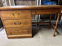 Front view of wooden student desk showing three drawers on left with metal handles and one long drawer on right missing one handle knob