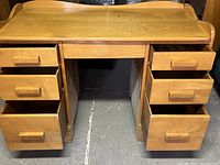 Front view of wooden desk showing drawers open and workspace