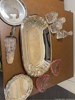 Overall view of silver plated serving items and glass decanters on a dark surface