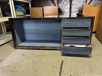 Front view of wooden wardrobe showing shelving on left and three drawers on right, bottom drawer open.