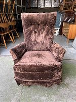 Front view of brown velvet swivel rocker chair showing tufted backrest, armrests, and skirted bottom.