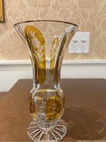 Front view of the glass vase showing amber yellow vertical panels with etched white flowers and flared rim