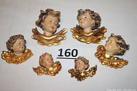 Six carved wood cherub head sculptures laid out on white surface