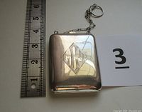Front of closed rectangular case showing engraved monogram, ruler for scale and key ring