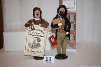 Both Charles Dickens and public crier figures displayed side by side from front