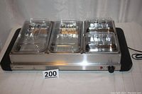 Front angled view showing buffet server with four covered warming sections and temperature control knob on right side.