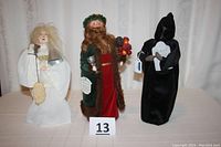 Three Byers' Choice 'A Christmas Carol' spirit figurines displayed side by side on white surface.