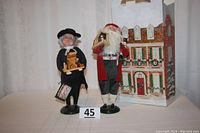 Both Christmas figures together showing German Santa in red and clergyman in black with holiday gift bag background.