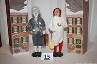 Two figures displayed side by side in front of decorative building backdrop, Scrooge in white nightgown and Marley in gray robes with chains, each on a green base.