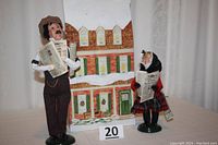 Front view of both figures by Byers' Choice Ltd holding newspapers, standing on a table.