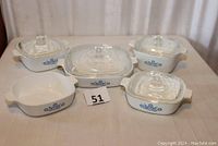 Five vintage CorningWare casserole dishes with blue cornflower pattern, four have lids, one missing lid.