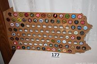 Full view of the wooden Pennsylvania shaped board with over 60 beer bottle caps in place and empty slots for more.