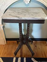 Full view of the Victorian lamp table showing marble top and carved walnut base with castor wheels.