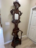 Full view of the walnut hall tree showing mirror, pegs, umbrella stand base, and overall height and shape.