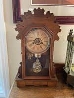 Front view of full wood case clock on table with decorative framing