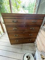 Full front view of the large walnut chest of drawers with five drawers, showing the brass drawer handles and keyhole escutcheons.