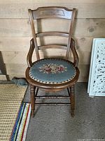 Full view of walnut straight chair showing three horizontal slats on backrest and round seat with floral needlepoint upholstery.