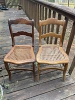 Both chairs together showing wooden frames and cane seats on a wooden deck.