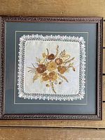 Overall framed pressed flower arrangement showing the lace-bordered linen with flower bouquet display in elaborate dark wood frame.