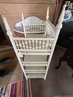 Angled view of the white painted Victorian Stick & Ball linen rack showing its four vertical posts and multiple horizontal shelves.