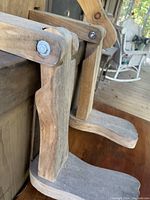 Close-up photo of the articulated wooden figure's arm and shoulder joint showing the thick 2-inch lumber and fastening hardware