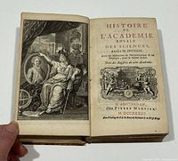 Open book showing detailed engraved frontispiece and title page in French with date 1733 from Amsterdam publisher Pierre Mortier.