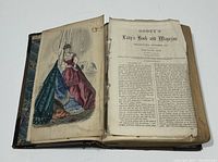 View of open book showing color fashion plate on left and black and white text page titled 'Godey's Lady's Book and Magazine' on right.