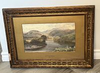 Full view of framed watercolour landscape painting featuring mountains, river and trees, signed and dated on matte below image.