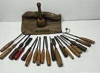 Full lot display with all 19 chisels, wooden mallet, Sur-Seg sharpening stone in box, and canvas drawstring bag on white background