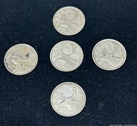 Top view showing all five Canadian silver quarter coins on black background.
