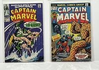 Two Captain Marvel comics side by side, Issue #4 and Issue #26, showing front covers in protective bags and boards.