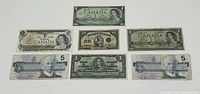 Seven old Canadian banknotes arranged for display. Includes 1923, 1937, 1954, 1967, 1973, and two 1986 series banknotes.
