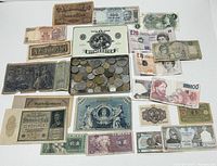 Overview photo showing scattered old world banknotes around an open Ritmeester Major tin box filled with assorted coins.