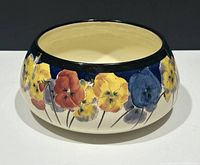 Full view of the round shallow bowl showing pansy decoration and dark blue rim