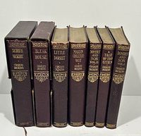 Front view of 7 Charles Dickens books in slipcases and softcovers showing titles and condition on spines