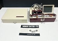 Full lot with Minori Editor PII device, user manual, and carrying case lid removed, showing components and wiring.