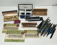 Full view of the lot showing pens, nib cards, and pen cases arranged on a white surface.