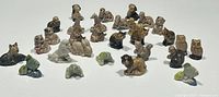 Photo showing a group of 29 small animal figurines including dogs, cats, owls and frogs arranged on a white surface.