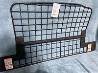 Front view of the black metal cargo separator with grid design and mounting brackets with labels.