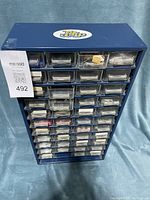 Full view of blue metal storage cabinet with 40 clear drawers storing electrical parts