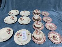 Full view of all dish bowls and plates arranged on fabric surface showing floral patterns and dish shapes.