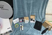 Full lot overview including satellite dish, modems, remote, and scanner all arranged on blue cloth
