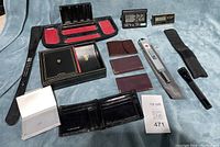 Overview of lot showing wallets, leather holders, clocks, Zippo lighter, Mini Maglite, shoehorn, tray with jewelry, change scoop, and accessories box