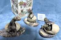 Photo showing all three baby dinosaur figurines on a fabric surface with Farmers Market decorative box in background.