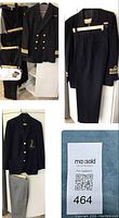 Full view of black Royal Navy Commander blazer with gold buttons and three pairs of black/navy trousers hung on hangers plus white shirt and tie on bed