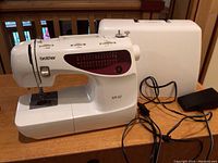 Brother XR-52 sewing machine and foot pedal with power cord on a wooden surface, with carrying case in background